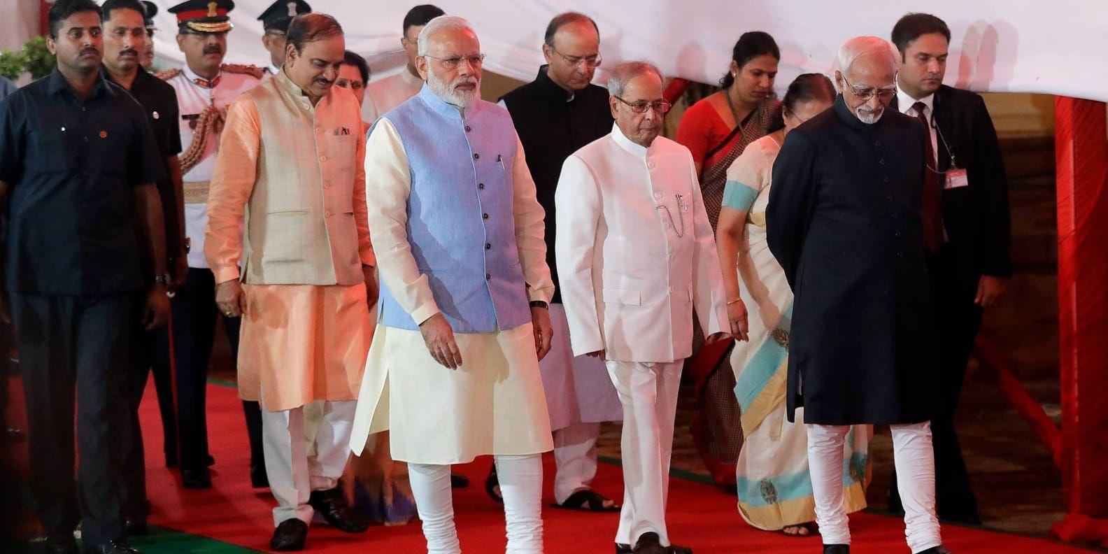 Premiärminister Narendra Modi i mitten, president Pranab Mukherjee till höger, samt vicepresident Hamid Ansari, går i procession till midnattsceremonin för lanseringen av skattereformen.