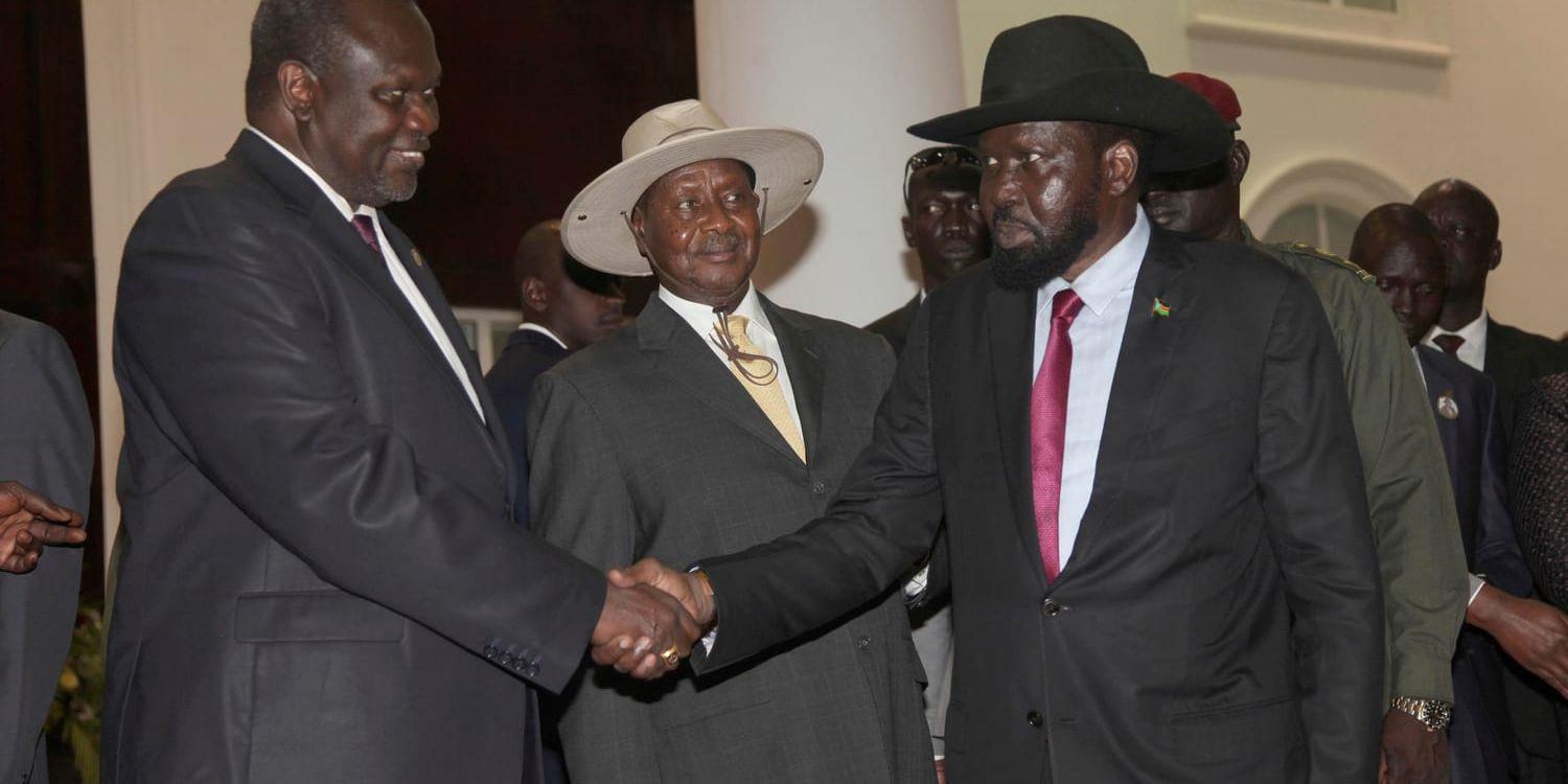 Sydsudans tidigare vicepresident Riek Machar, till vänster, skakar hand med president Salva Kiir när avtalet om maktdelning slöts i Uganda den 7 juli. Arkivbild.