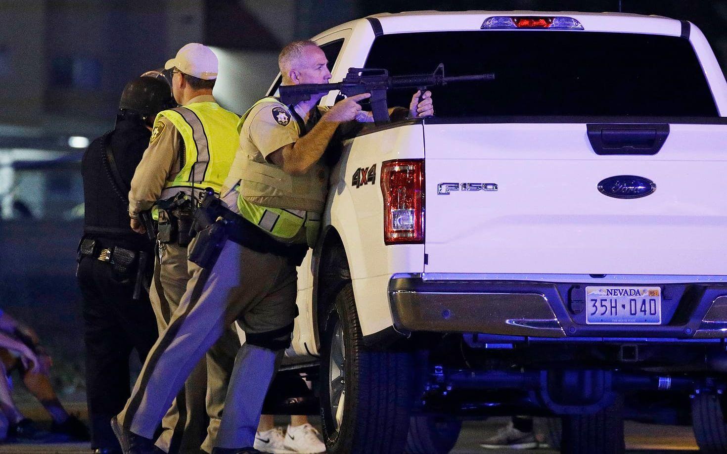 En polis tar skydd bakom en pickup i Las Vegas. FOTO: AP
