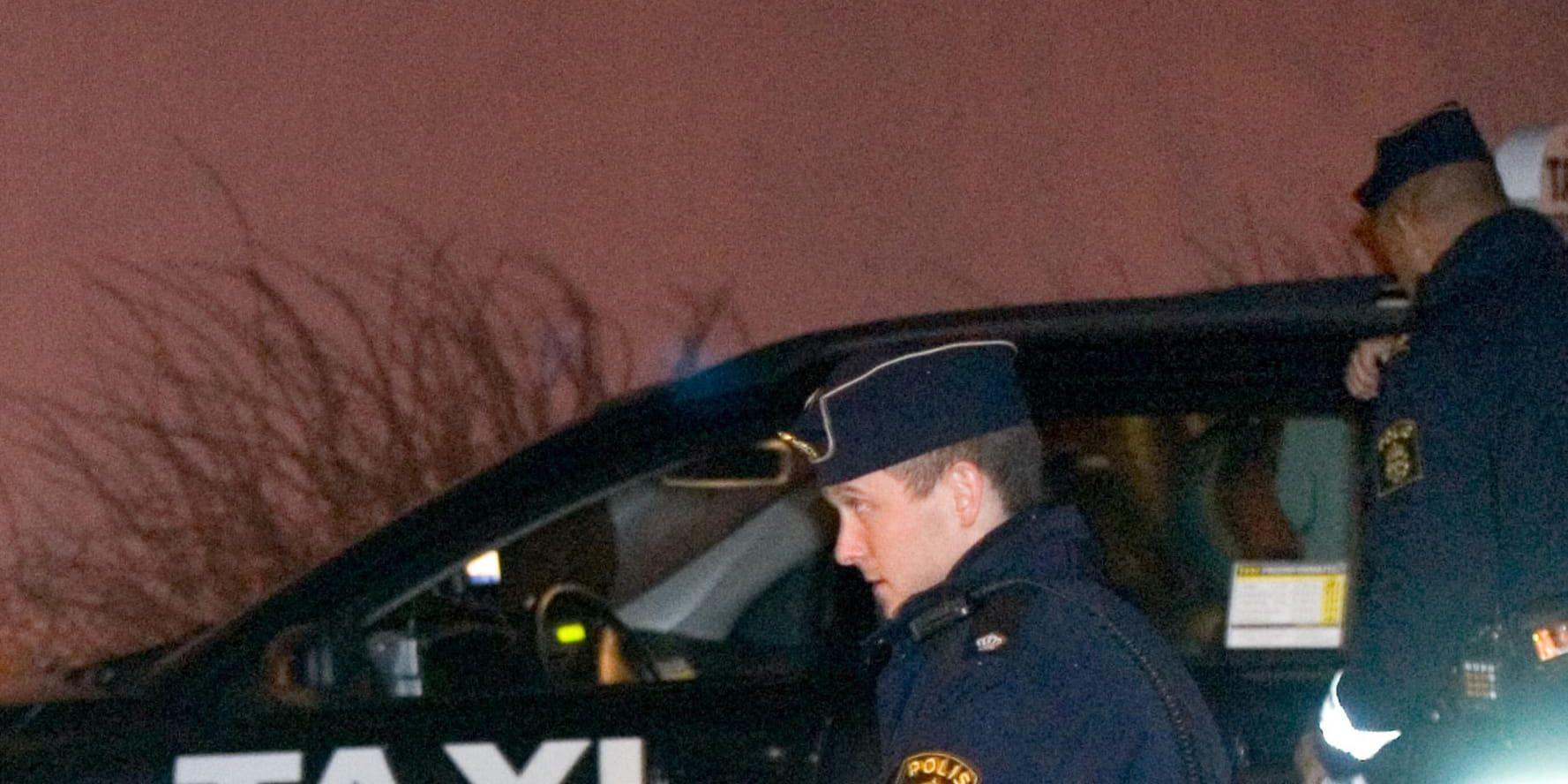 Två polismän på plats vid en taxi i Stockholmsområdet efter ett rån i december 2007. Arkivbild.