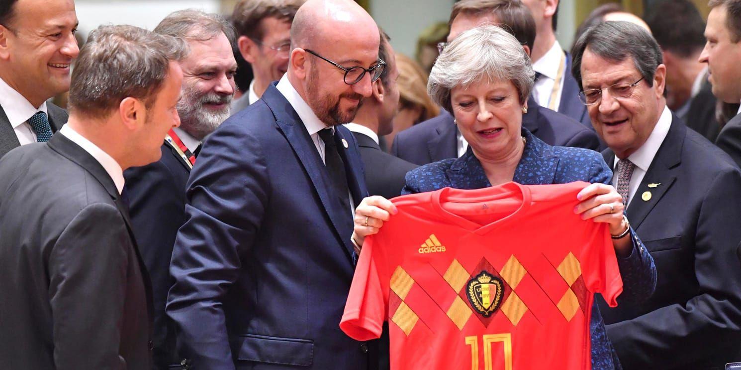 Belgiens premiärminister Charles Michel överlämnar en landslagströja till Storbritanniens Theresa May.