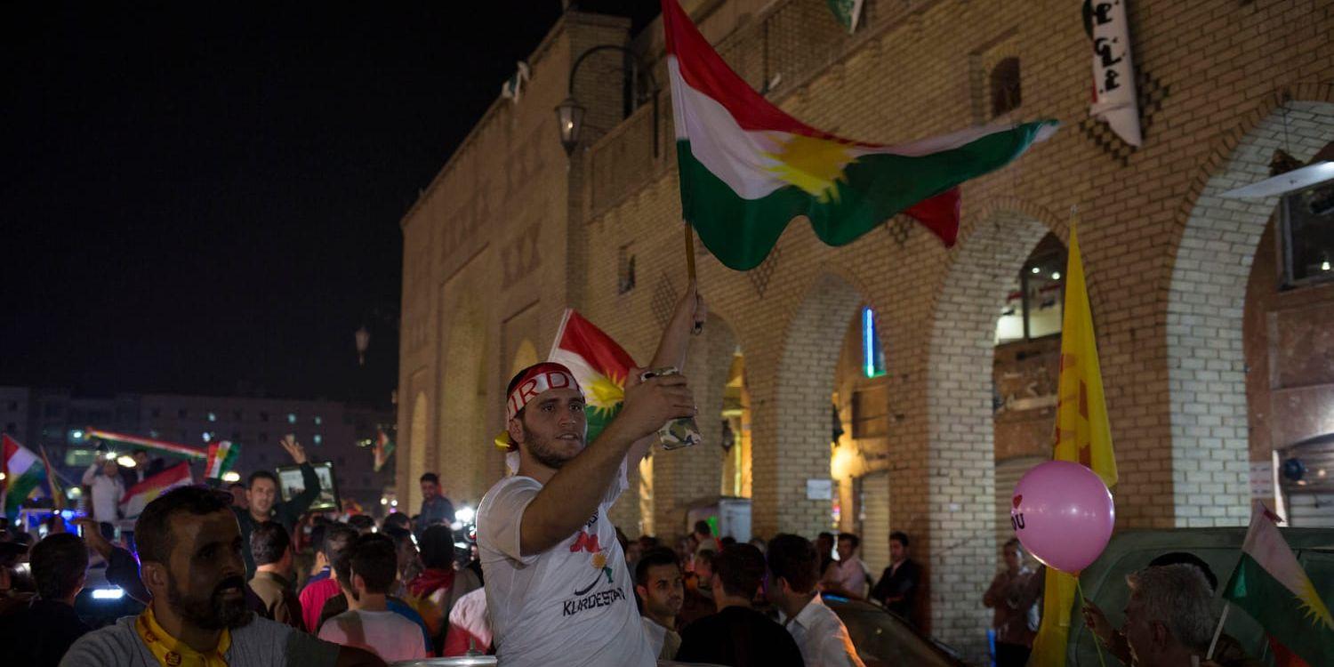 En man viftar med en kurdisk flagga utanför en vallokal.