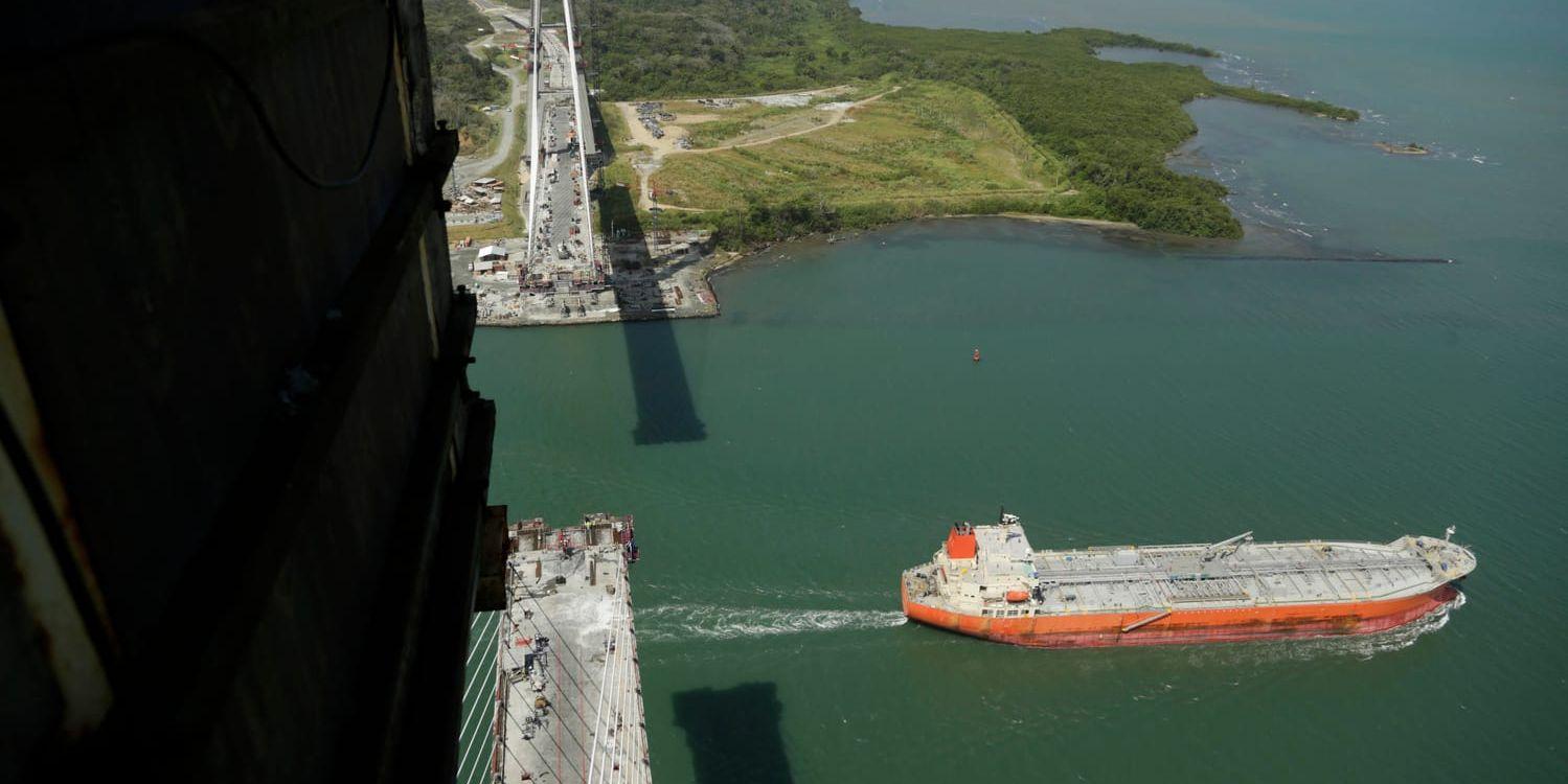 Ett fraktfartyg passerar under en ny bro som byggs över Panamakanalen i Colón.