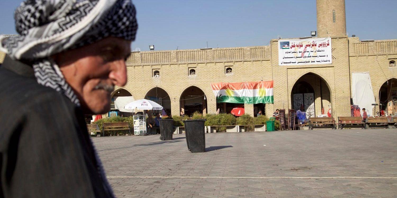 En äldre man i Arbil sitter intill en byggnad med valbanderoller inför måndagens folkomröstning i irakiska Kurdistan.