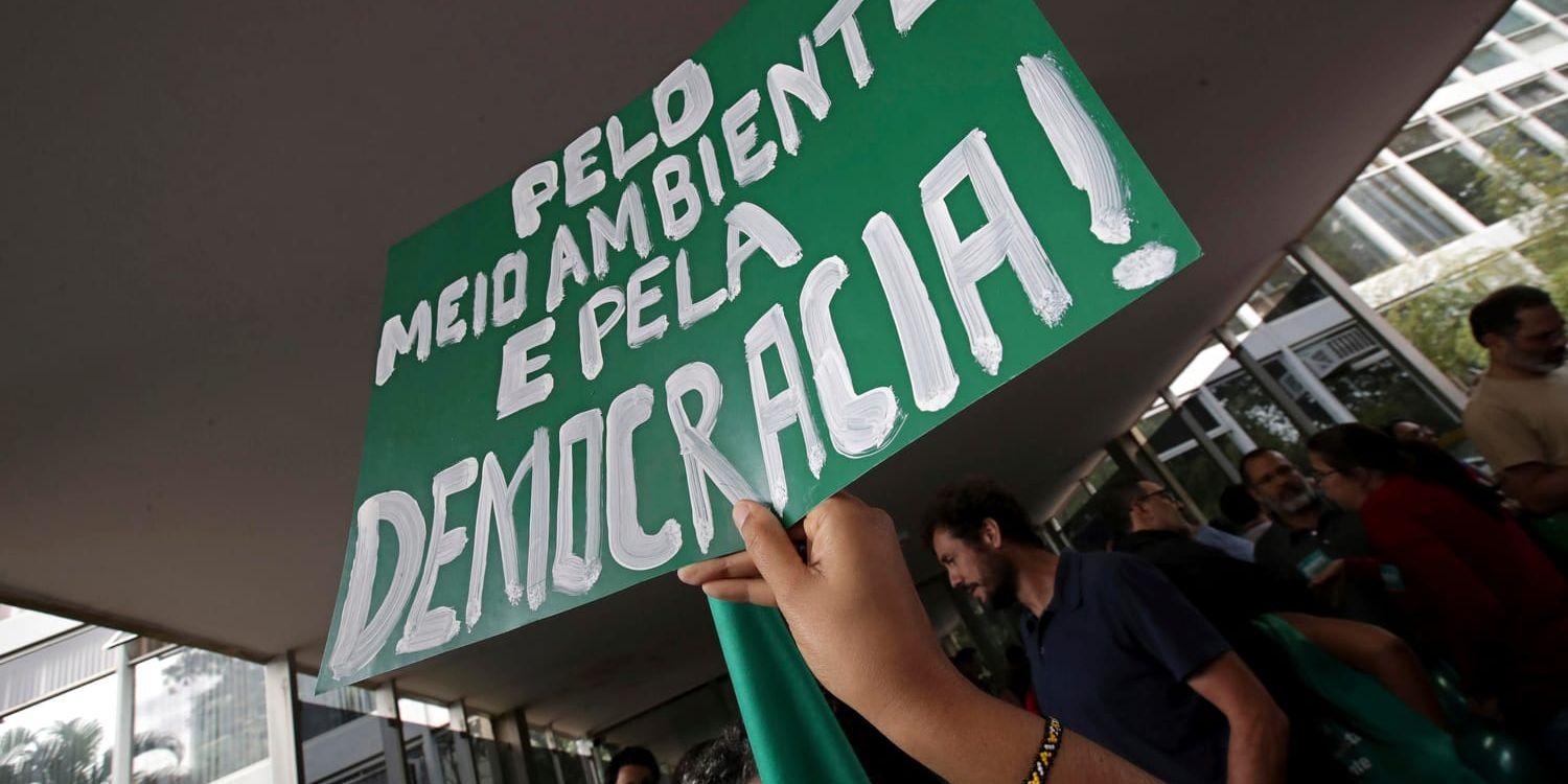 Miljöaktivister håller upp skyltar med orden "För miljö och för demokrati" under en protest i Brasiliens huvudstad Brasilia mot presidentkandidaten Jair Bolsonaro, vars klimatpolitik får kraftig kritik. Bilden är från 19 oktober.