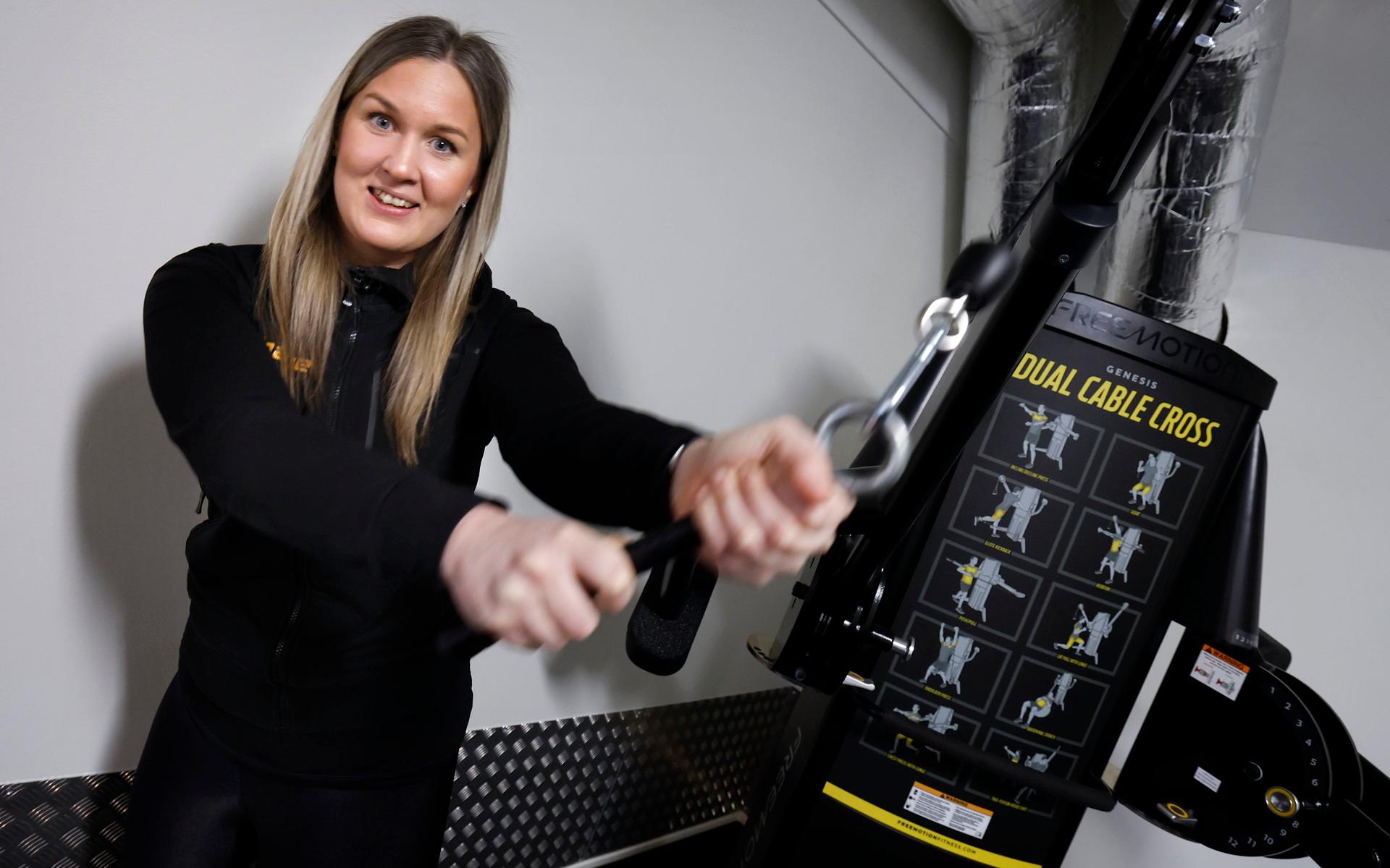 Ett golfhantag har monterats på en av gymmaskinerna. Sofie Andersson visar hur man kan träna sin golfsving.