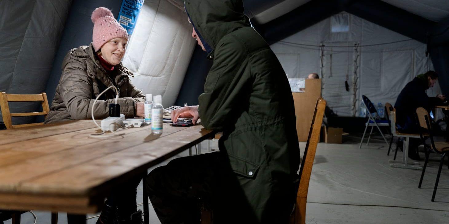 Ludmila, 47, laddar sin mobiltelefon och värmer sig i ett värmetält i Irpin utanför Kiev.