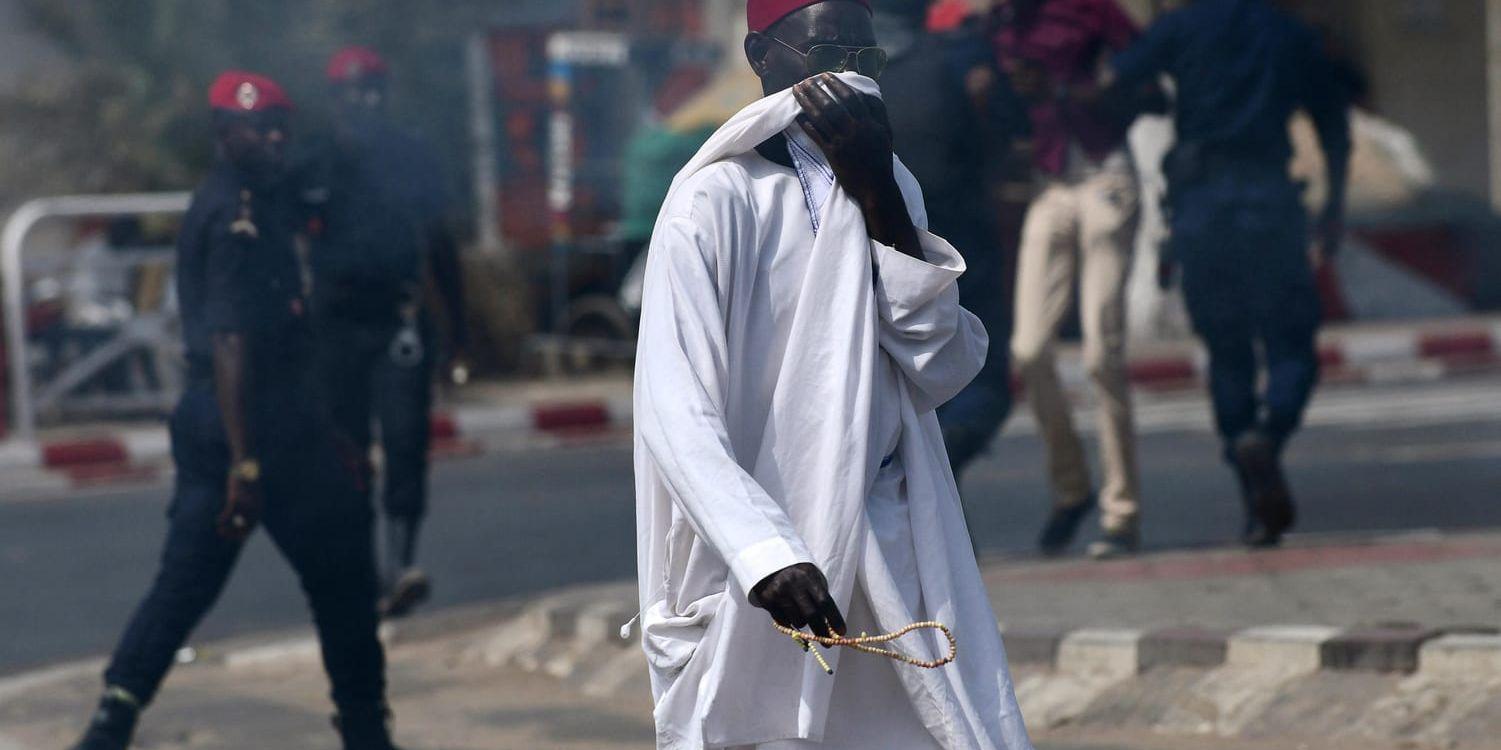 En man försöker skydda sig mot tårgas som polisen avlossat under fredagens demonstrationer i Dakar.