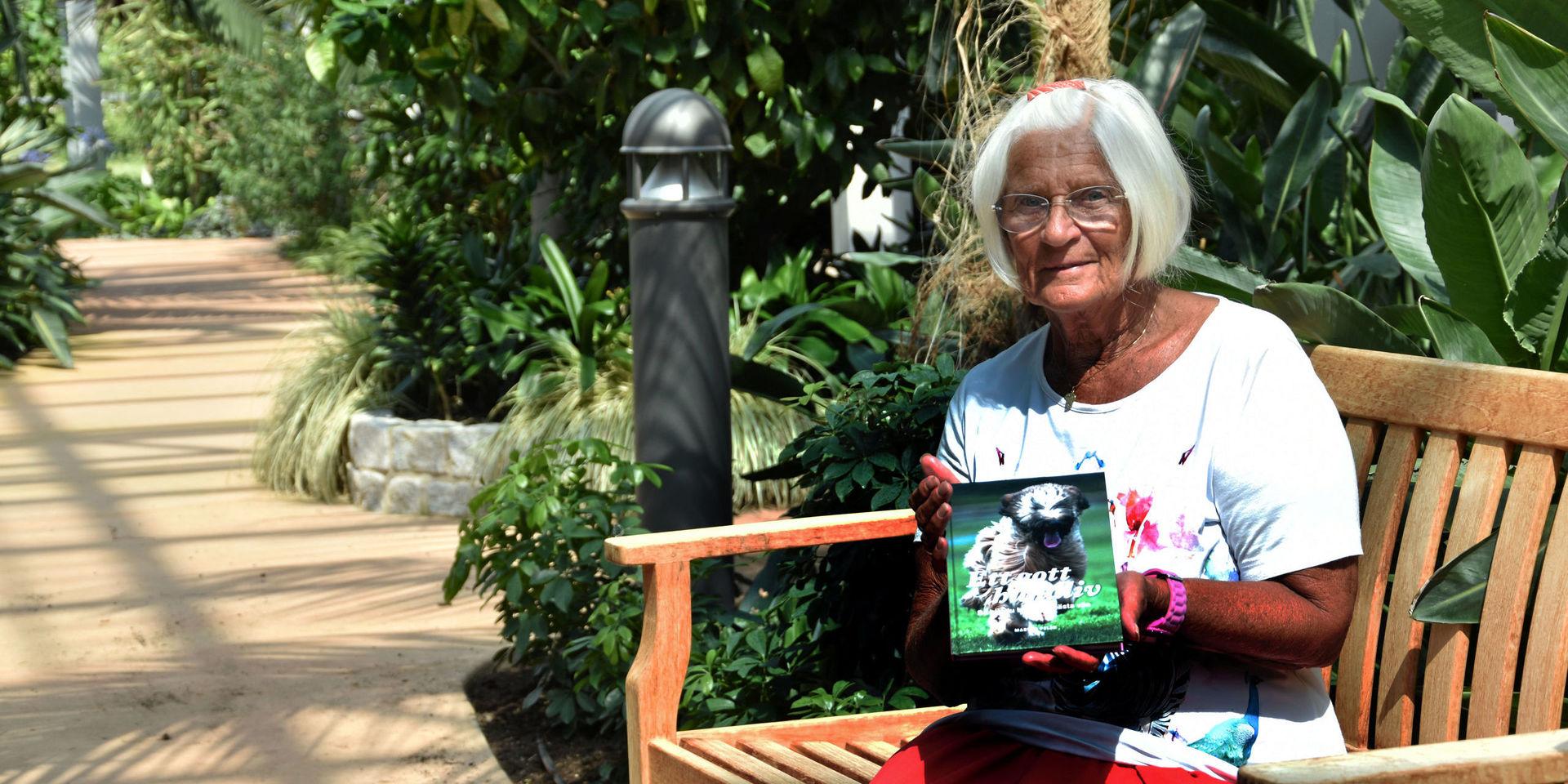Marian Pelér bor i bostadsrättsföreningen Bovieran i Breared och visar upp sin bok i den gemensamma inglasade trädgården.