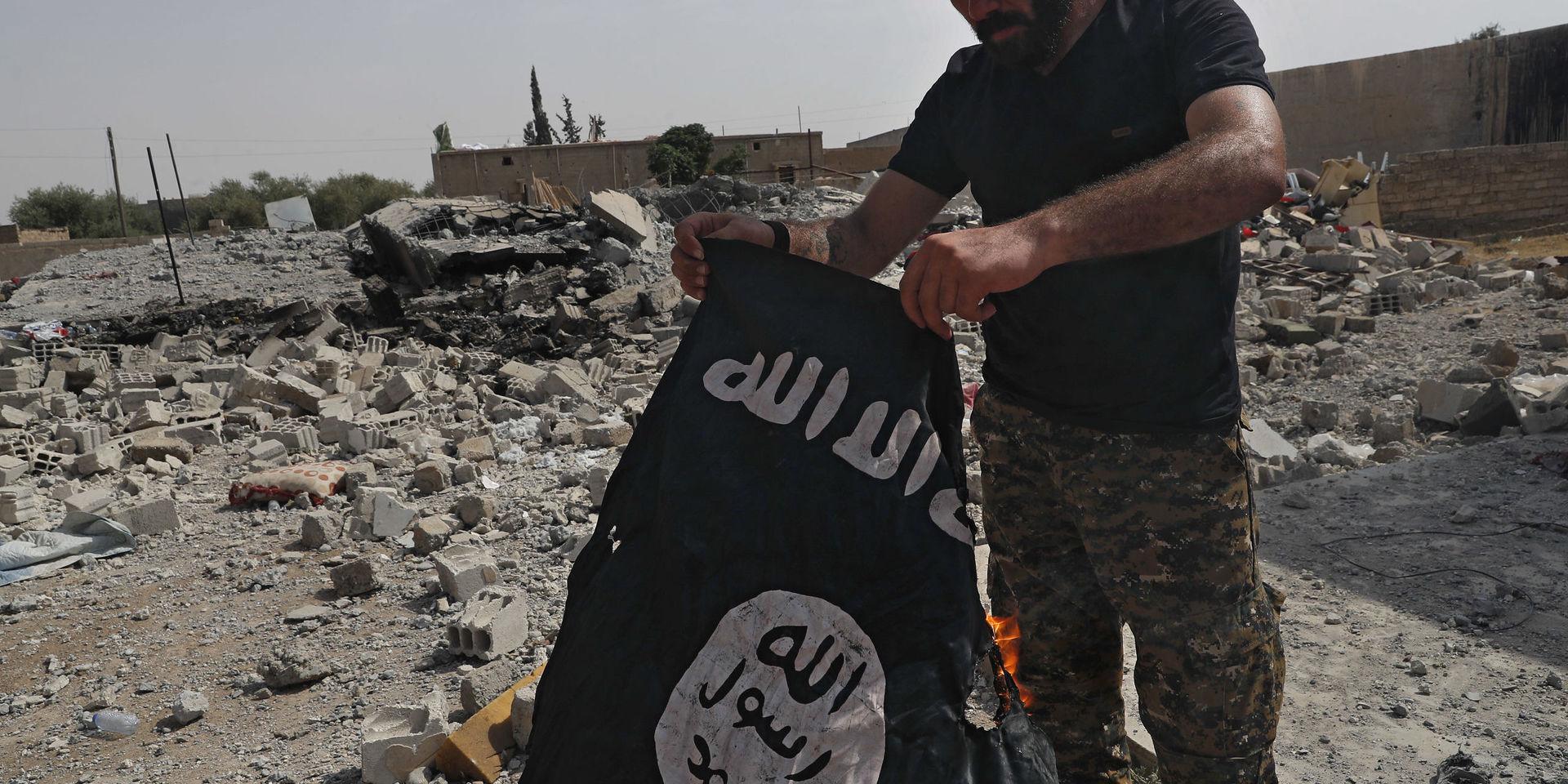 En man bränner en IS-flagga i al-Raqqa Syrien, juli 2017. Arkivbild.
