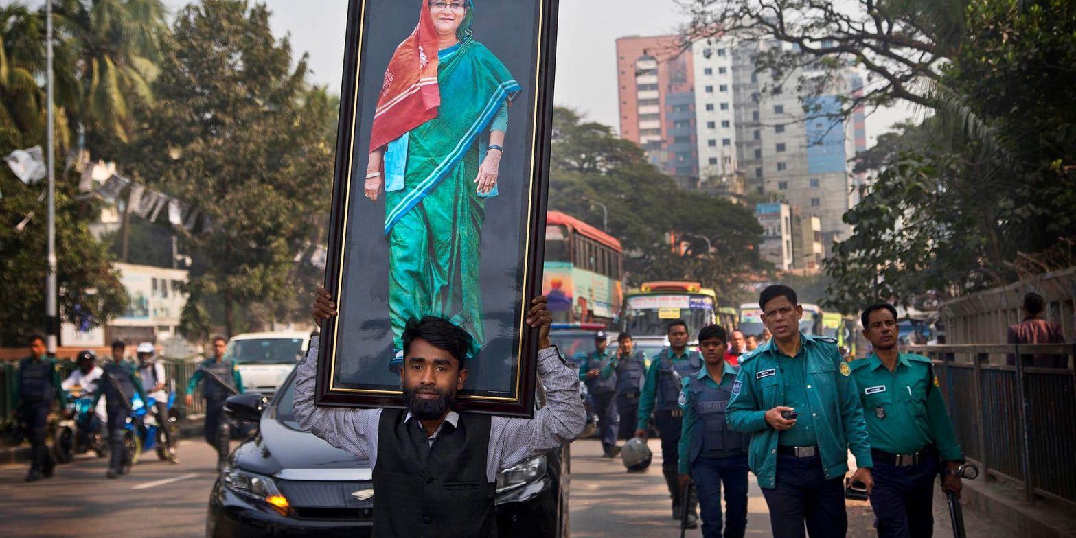 En anhängare av Awamiförbundet bär ett stort fotografi av premiärminister Sheikh Hasina under ett valmöte i Dhaka.