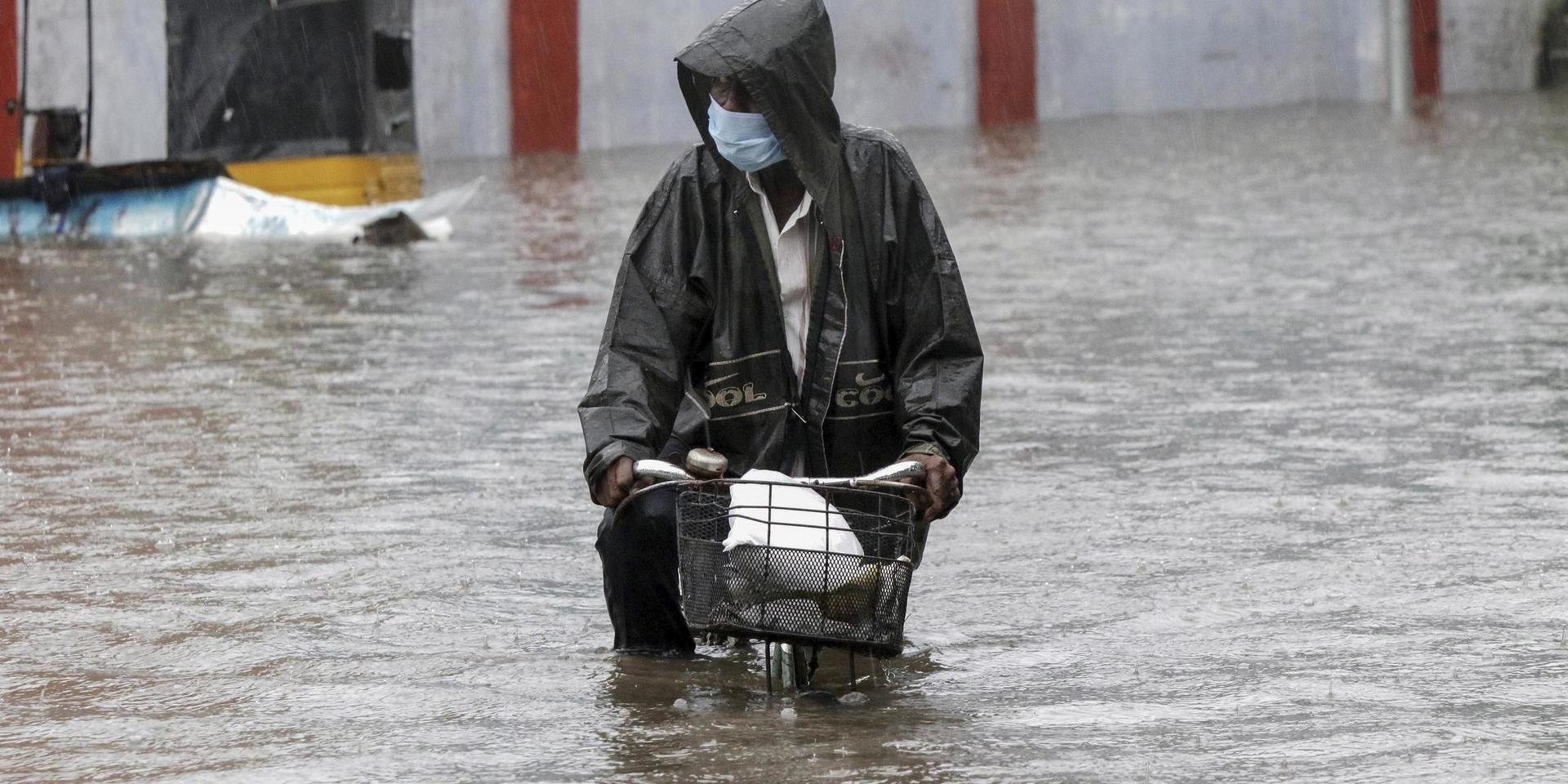 En man försöker att cykla över en översvämmad gata i Chennai i Tamil Nadu i Indien.