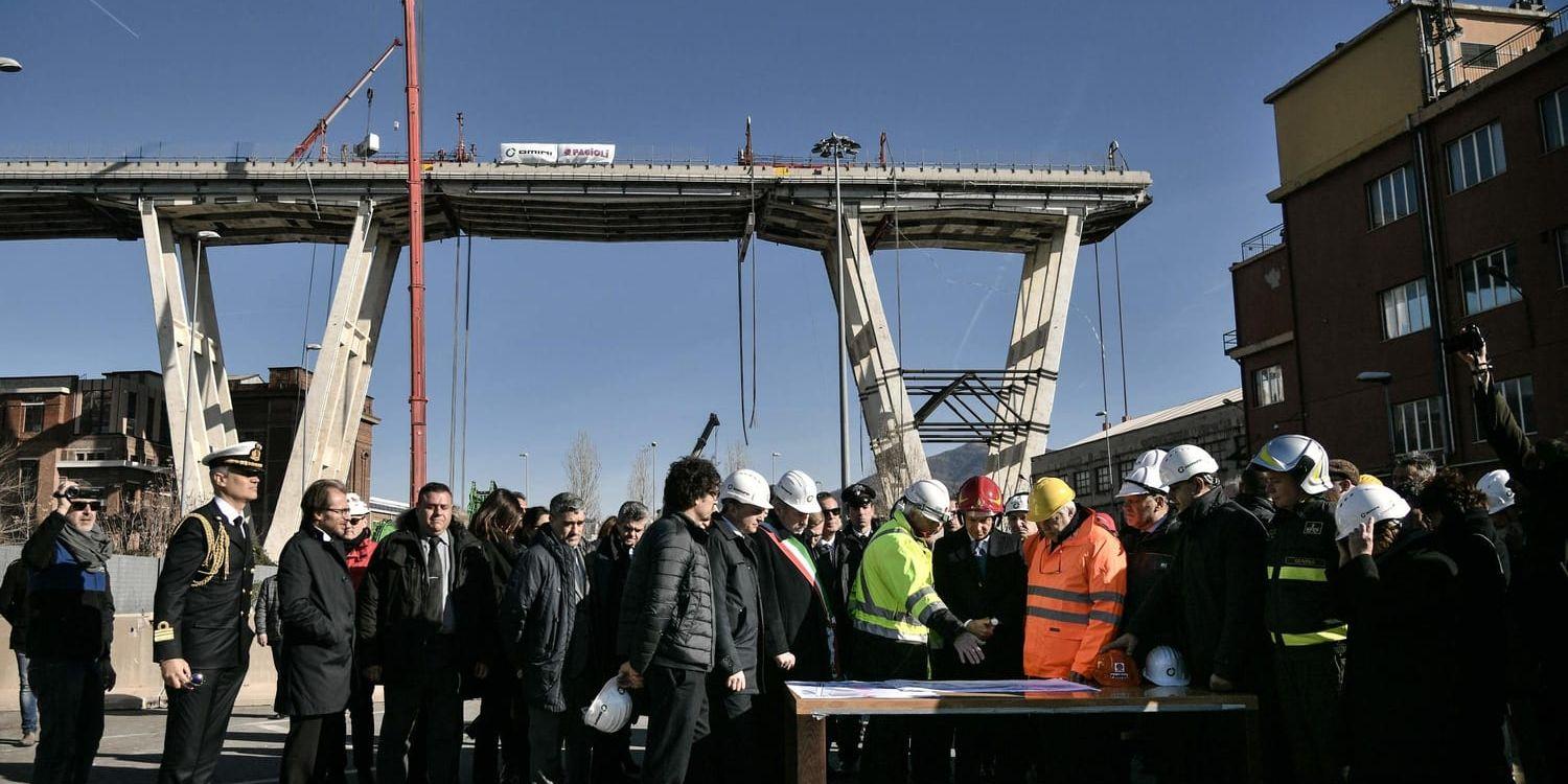 Italiens premiärminister Giuseppe Conte (med röd hjälp) framför resterna av Morandibron.