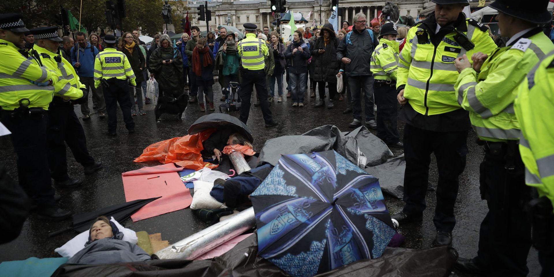 Extinction Rebellion climate change protesters lie with their arms locked together blocking a road at the bottom of Trafalgar Square in London, Friday, Oct. 11, 2019. Some hundreds of climate change activists are in London during a fifth day of protests by the Extinction Rebellion movement to demand more urgent actions to counter global warming. (AP Photo/Matt Dunham)  LMD113