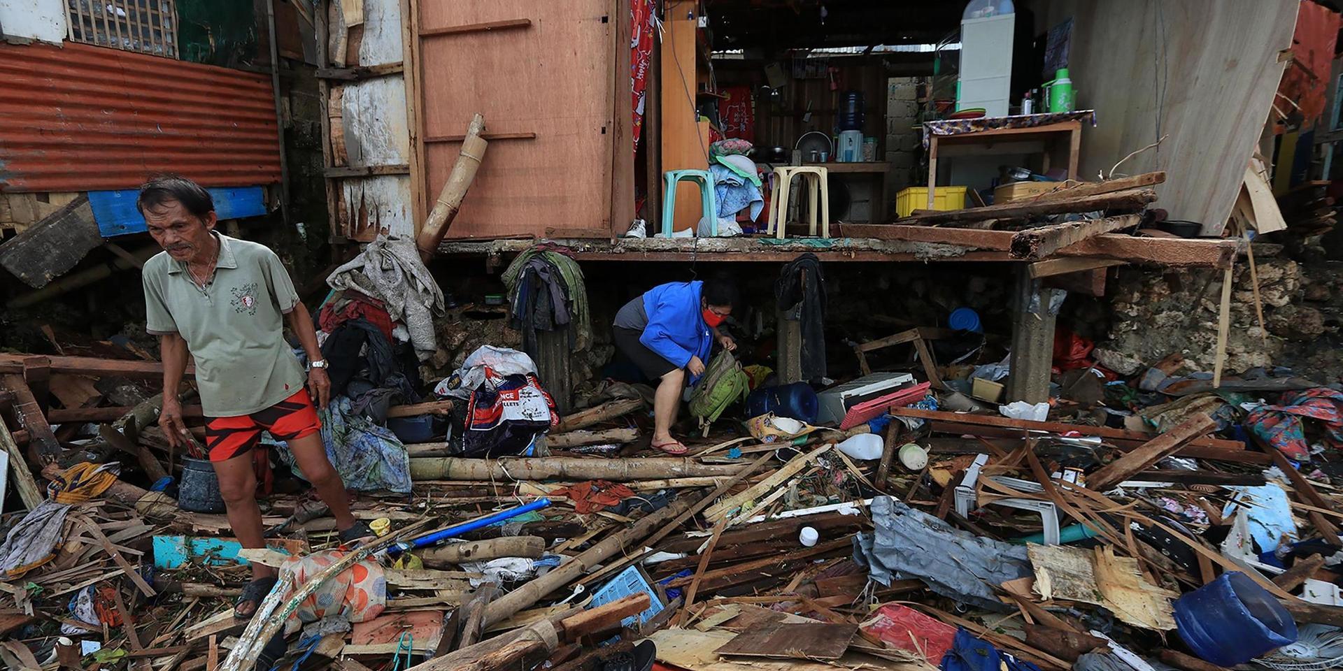 Boende försöker rädda föremål från sina förstörda hus i staden Lapu-Lapu efter kraftiga oväder i lördags.