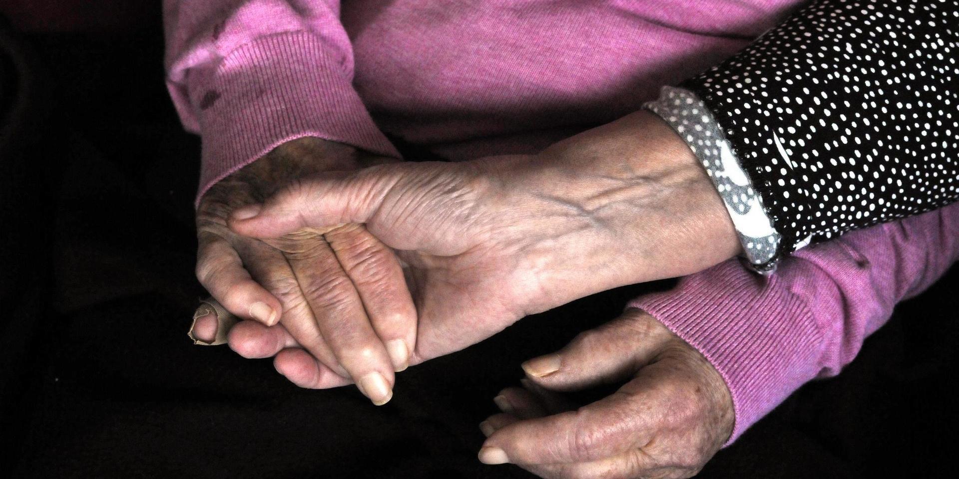 Kvinna håller en äldre kvinnas händer.