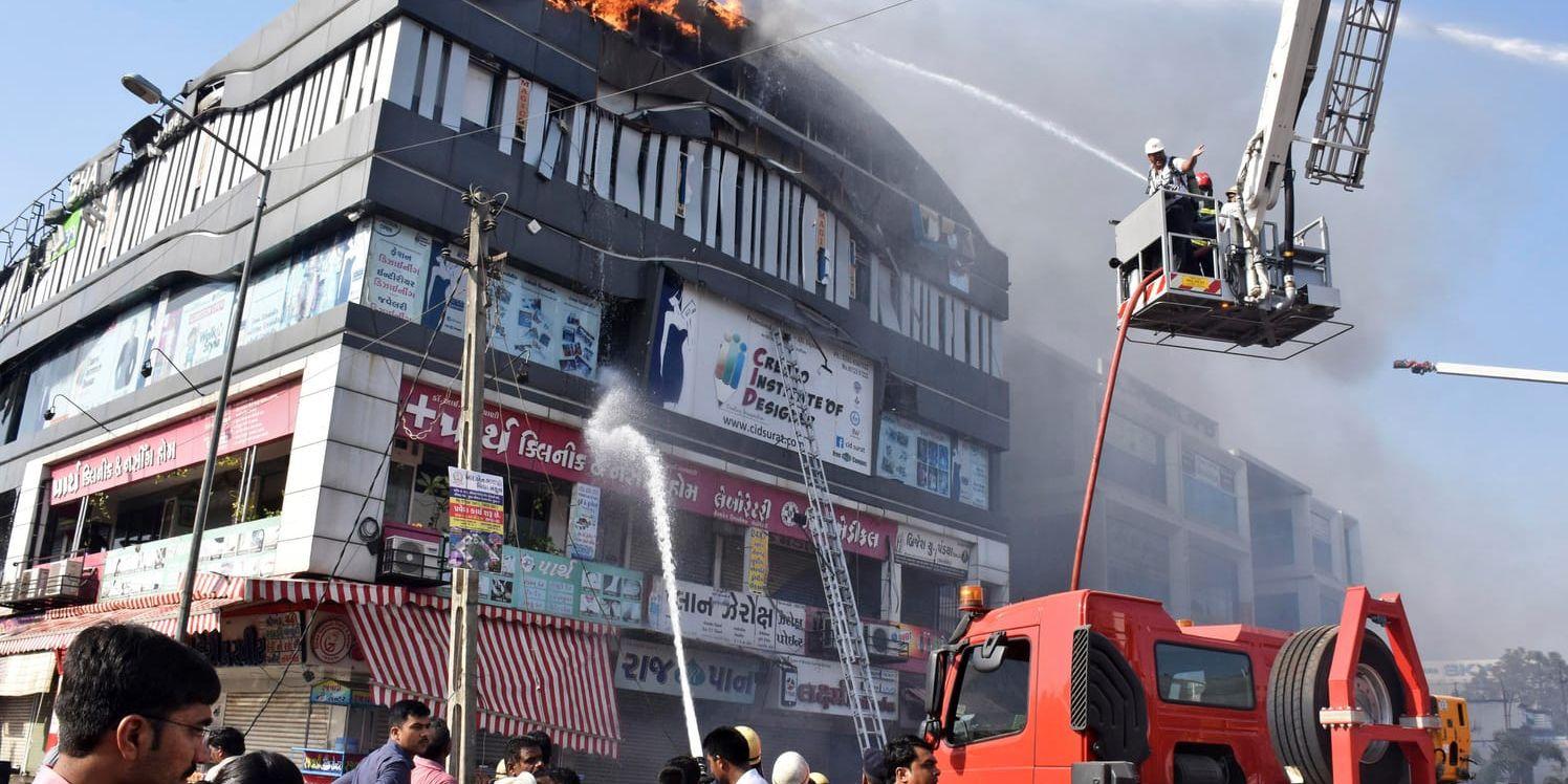 Räddningstjänsten bekämpar elden i flervåningshuset i Surat i västra Indien.