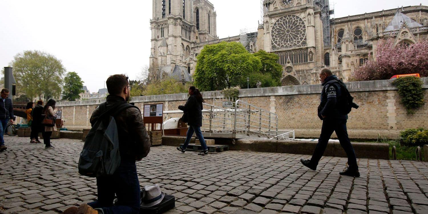 En man knäböjer framför Notre-Dame på tisdagen.
