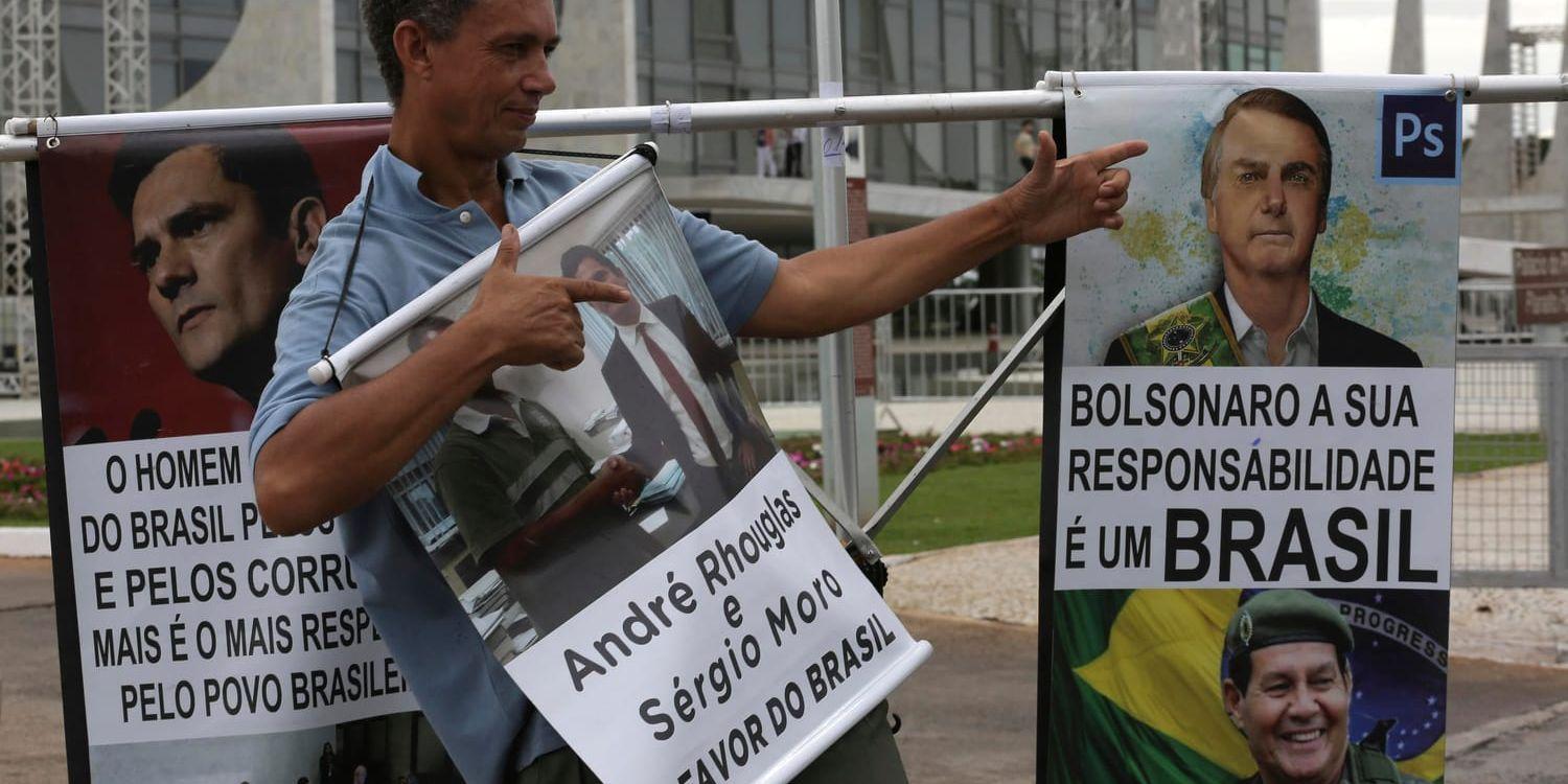 En anhängare av Jair Bolsonaro gör fingerpistoler framför affischer av honom, utanför presidentpalatset i Brasilia.