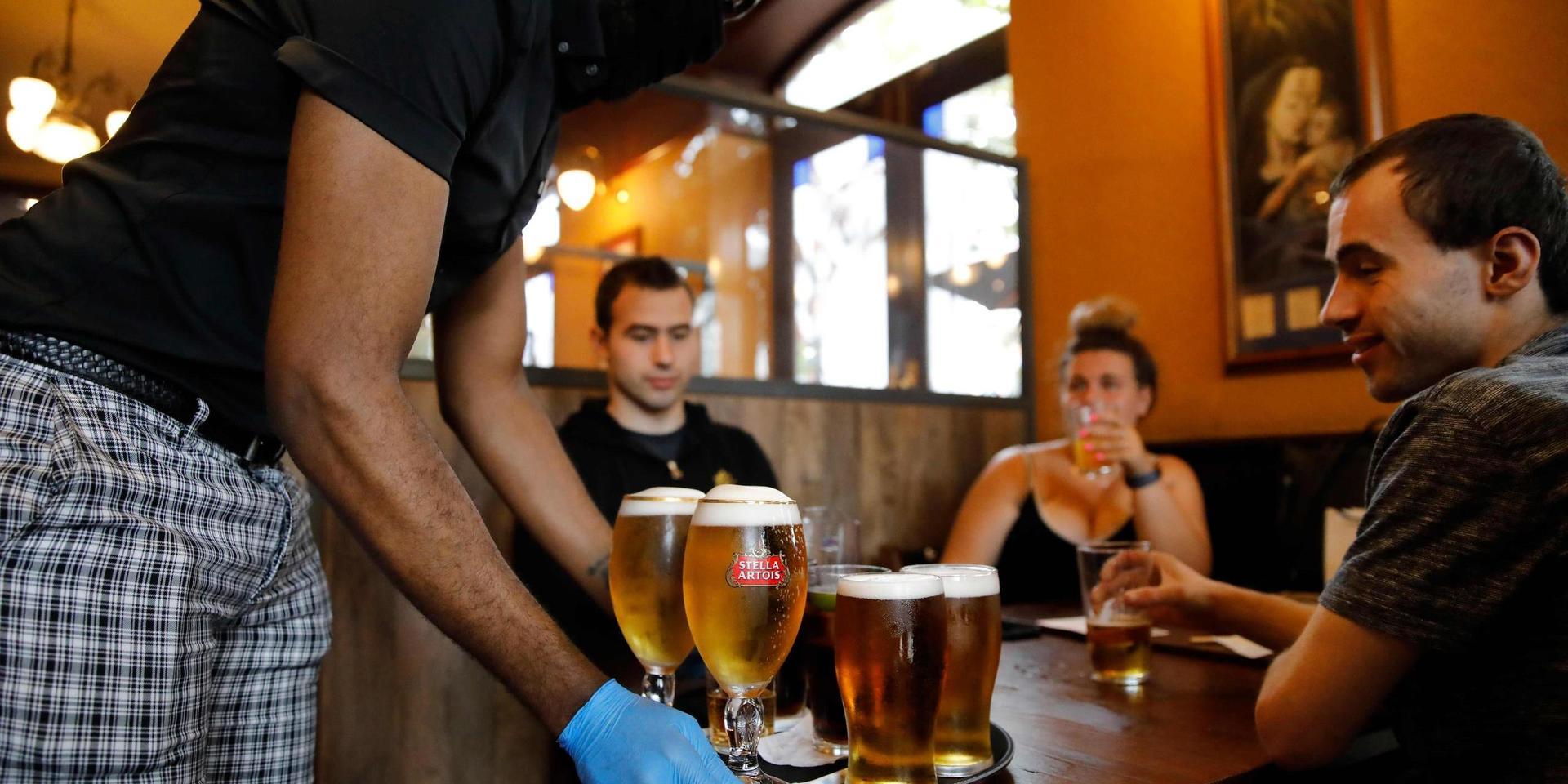 En servitör med skyddshandskar och munskydd serverar öl på lördagen till förväntansfulla gäster på en pub i Stratford i östra London. 
