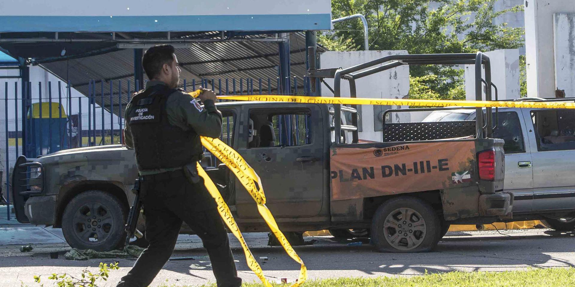 En mexikansk polis spärrar av platsen där ett av säkerhetsstyrkornas sönderskjutna fordon står. 