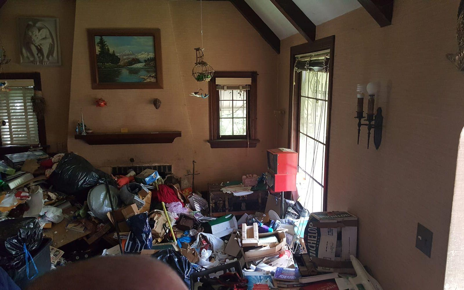<strong>FÖRE.</strong> Vardagsrummet var fullt av trasiga möbler, kläder och skräp. Foto: Redemption Construction