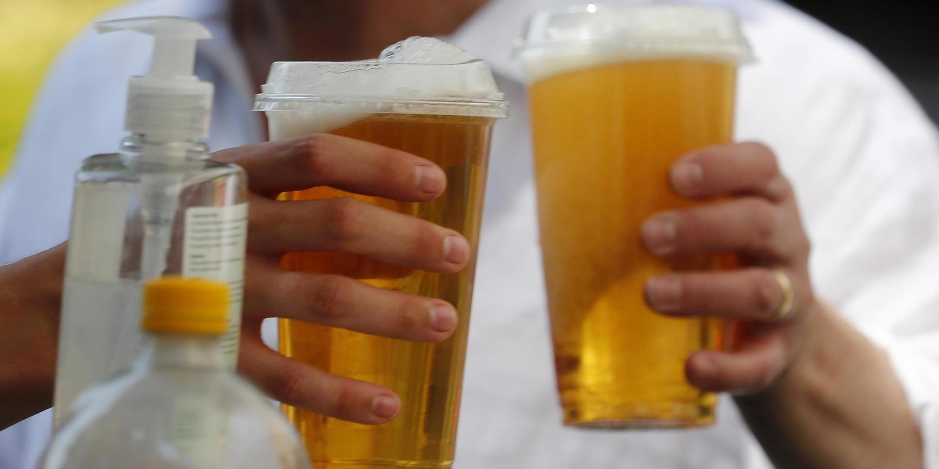 Öl i plastglas att ta med och en flaska handsprit bredvid. Snart kan engelsmännen njuta av en öl inne på en pub igen. 