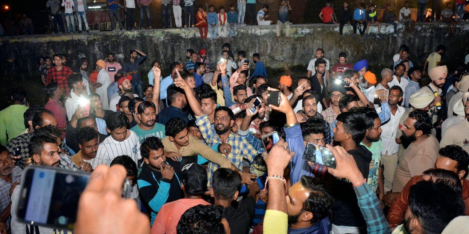 Upprörda människor samlas efter tågolyckan, som inträffade i samband med en festival i närheten av staden Amritsar i norra Indien.