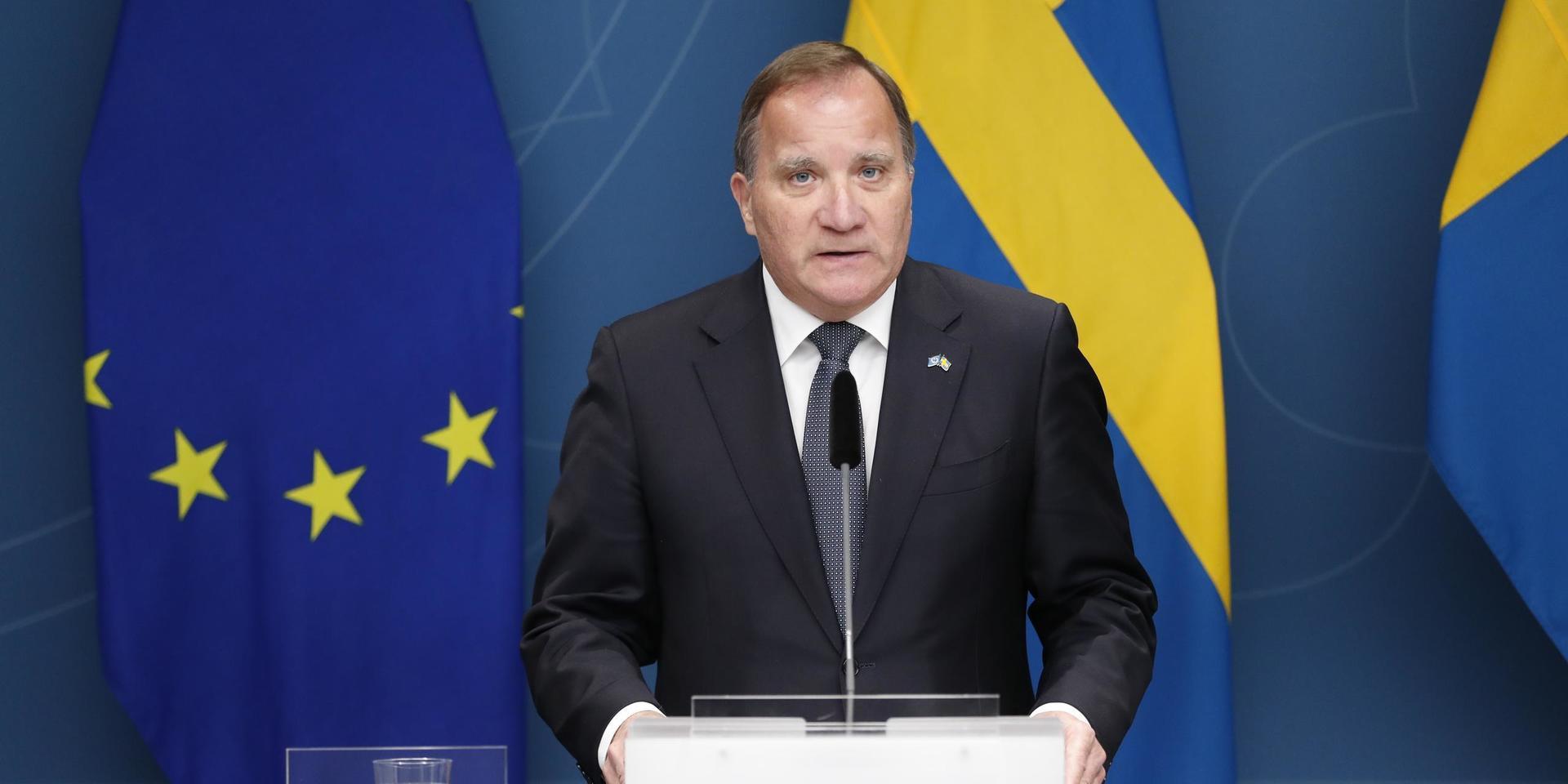 Statsminister Stefan Löfven vid pressträff. EU-flagga och svenska flaggan i bakgrunden.