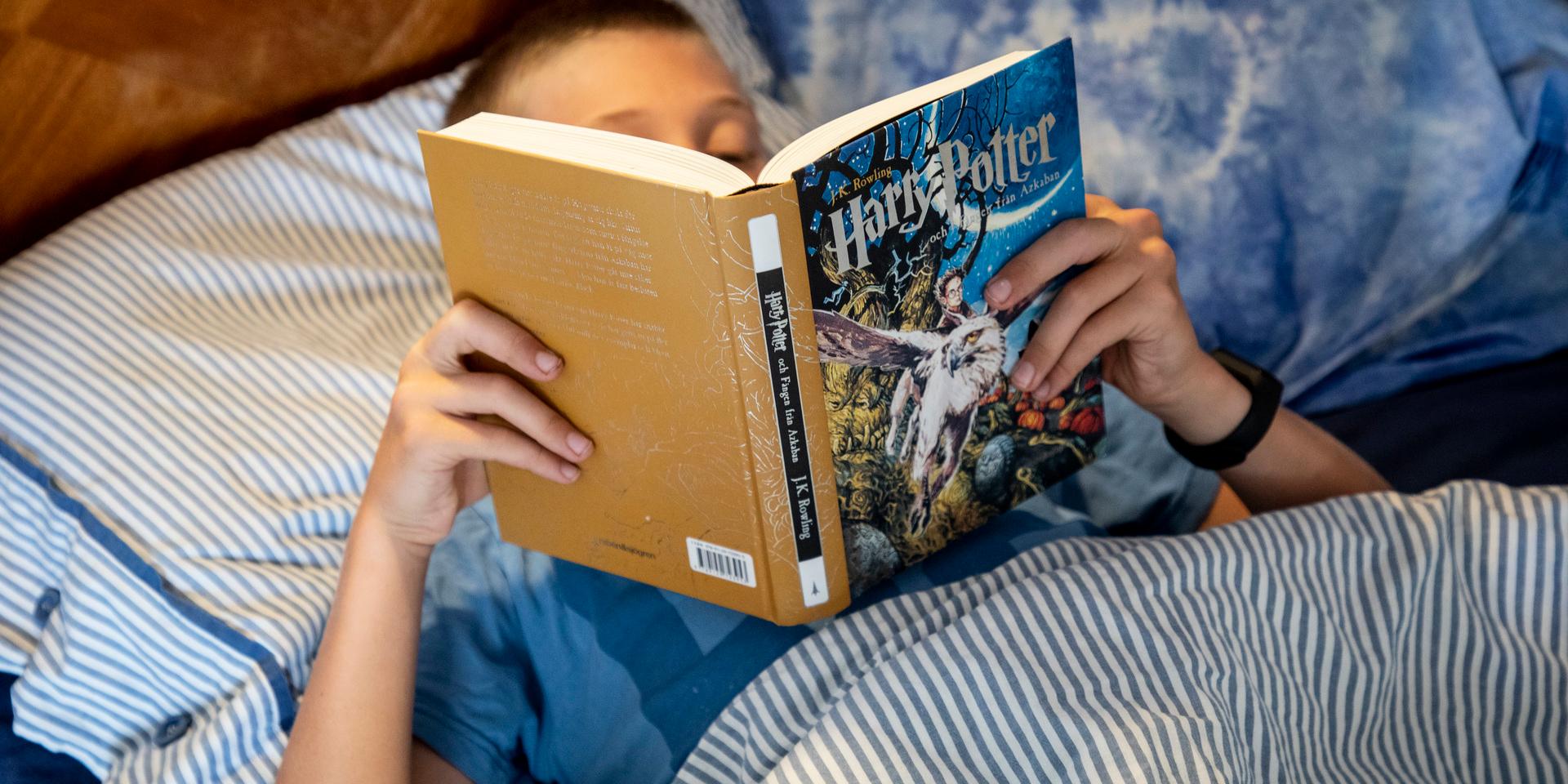 Ett barn läser en bok i en säng. Utmaningen är att få unga att fortsätta läsa i tonåren. Arkivbild.