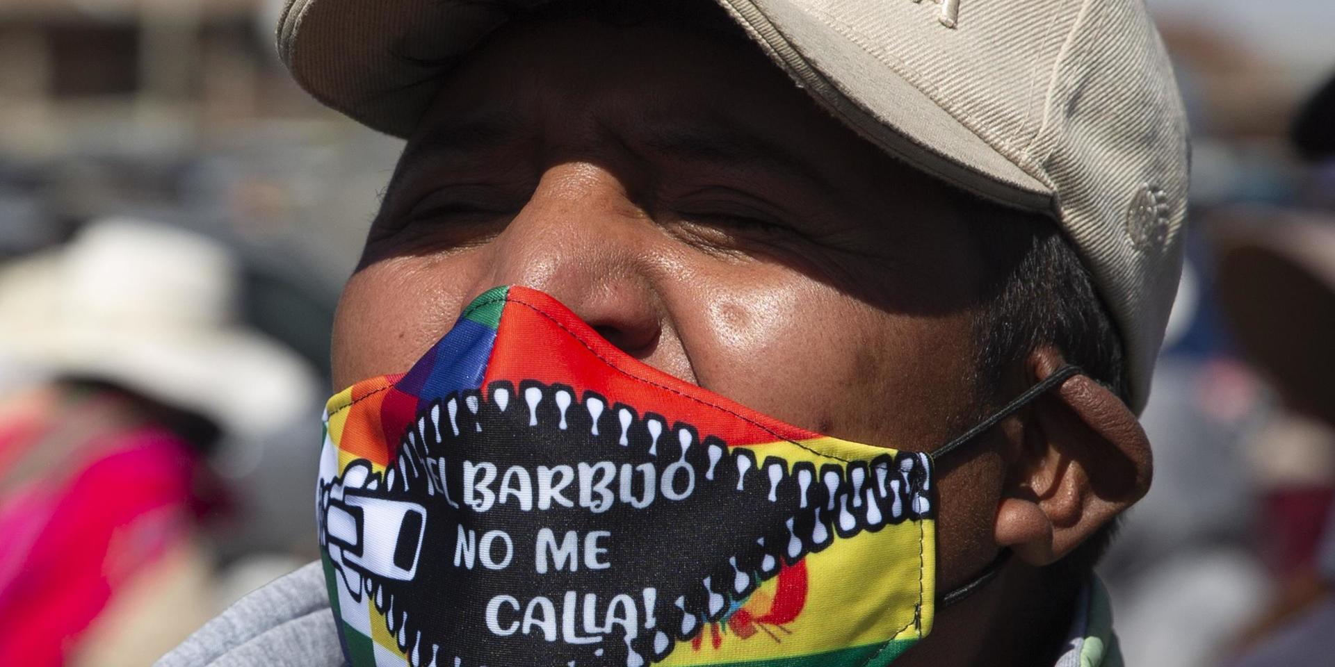 En demonstrant i El Alto bär en mask med texten 'Masken tystar inte mig!' under en protest mot att valet skjutits upp igen.