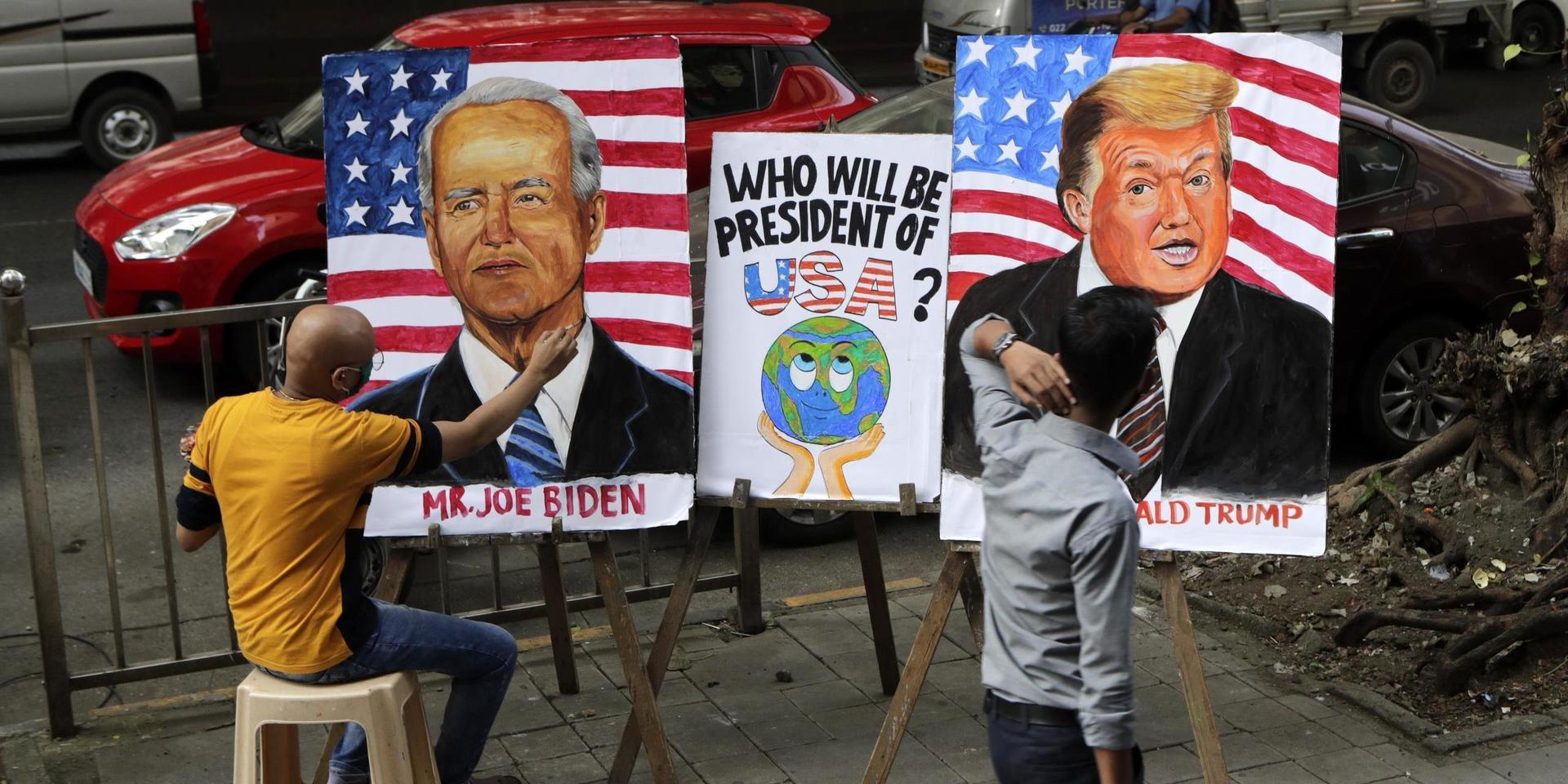 Indian art teacher Sagar Kambli makes paintings of President Donald Trump and Democratic rival Joe Biden on a pavement outside his art school remaining closed due to the COVID-19 pandemic in Mumbai, India, Thursday, Oct. 29, 2020. (AP Photo/Rajanish Kakade)  RKD101