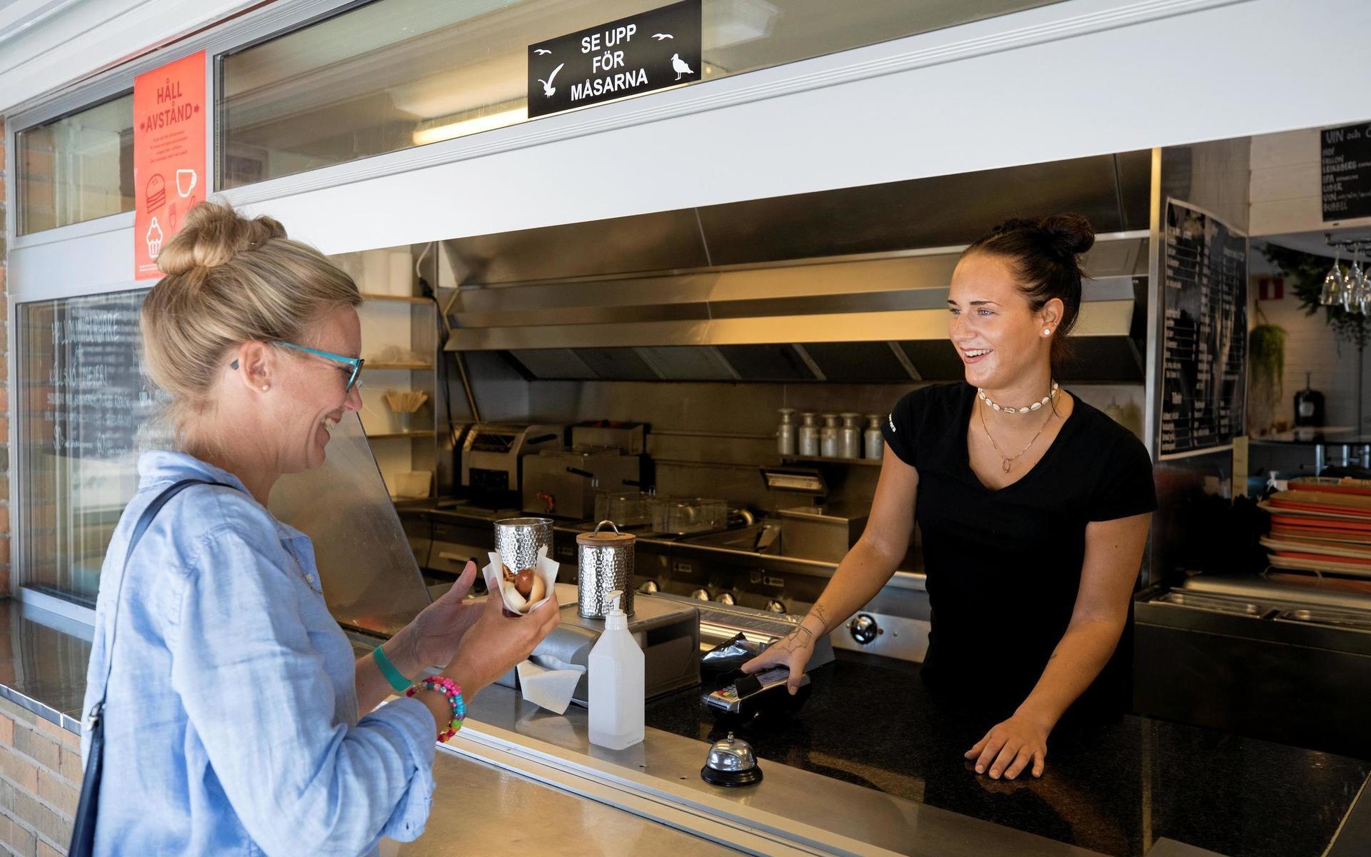Amanda Olsson på Torggrillen serverar korv med bröd till HN:s reporter Rebecka Kvint.