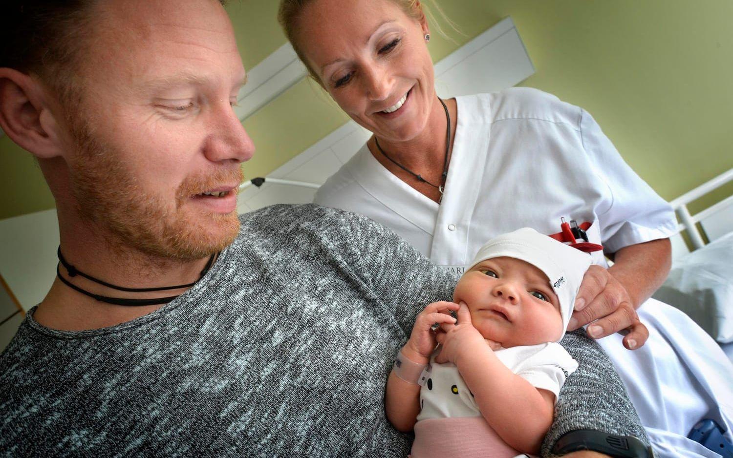 Mikael Krantz håller sin lilla dotter, en av rekordmånga bebisar födda på Varbergs BB i sommar. Till höger Charlotte Seum, barnmorska.