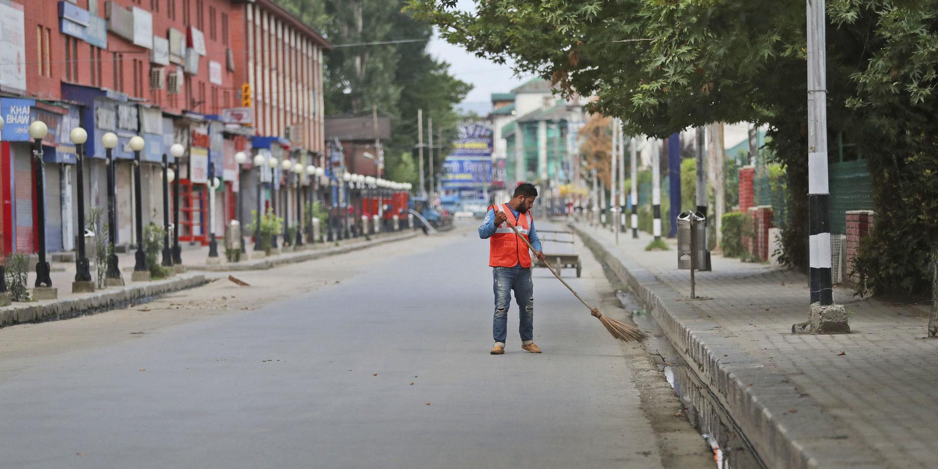 En arbetare städar gatan i staden Srinagar i Indienkontrollerade Kashmir under utegångsförbudet. 