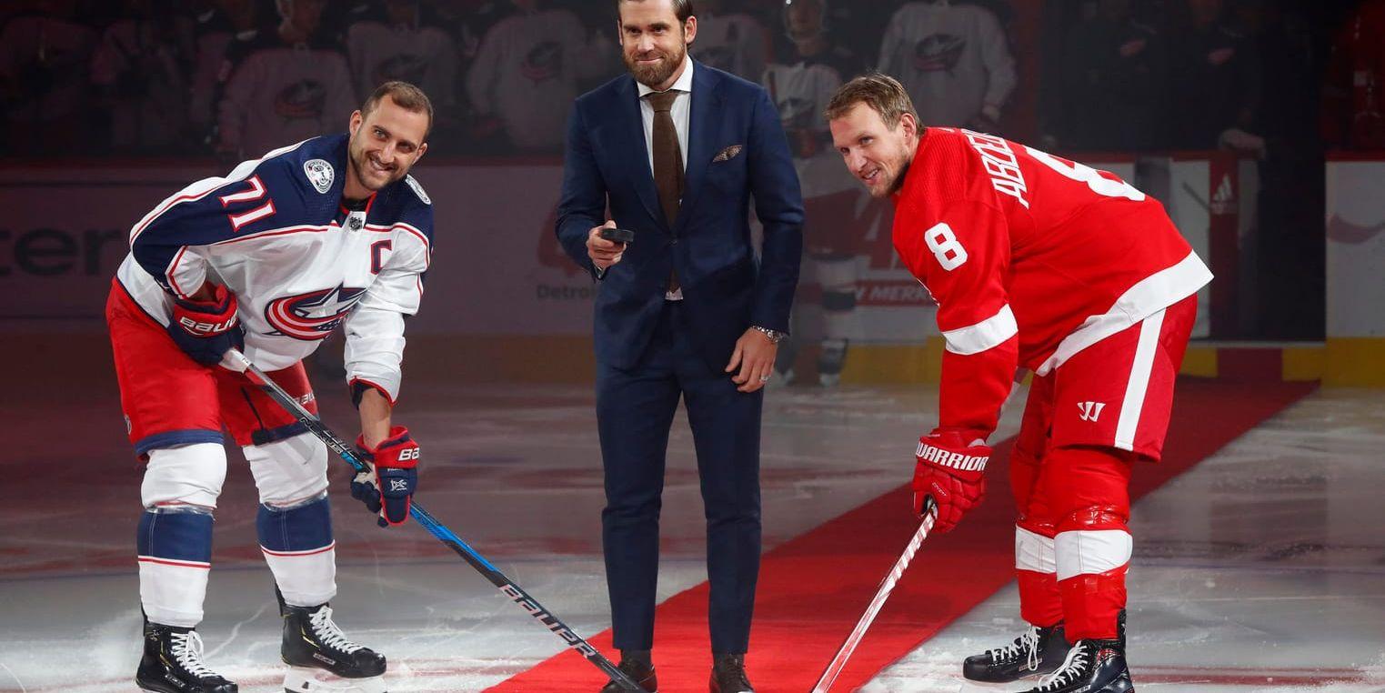 Henrik Zetterberg släpper pucken i ett ceremoniellt nedsläpp mellan Columbus Nick Foligno och Detroits Justin Abdelkader i NHL-premiären.