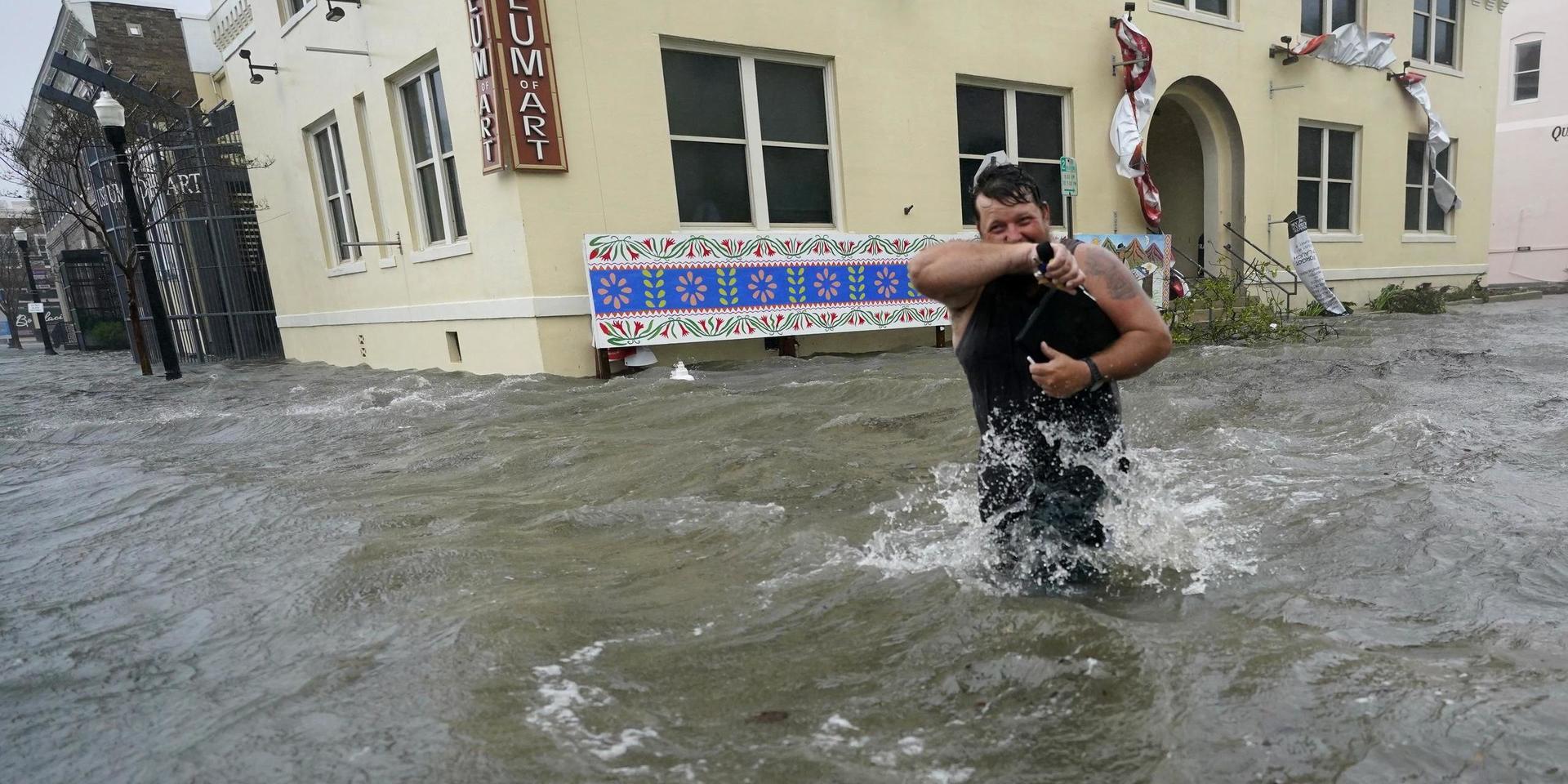 En man kämpar mot vattenmassorna i Pensacola i amerikanska Florida.