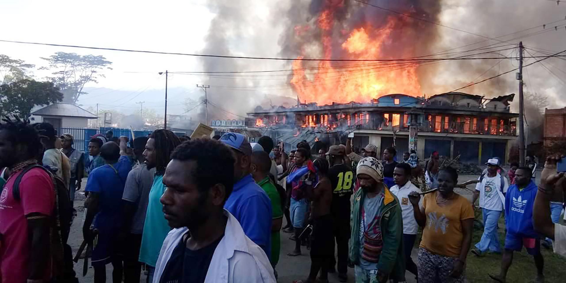 Folk samlas utanför butiker som satts i brand i Wamena i Papua.