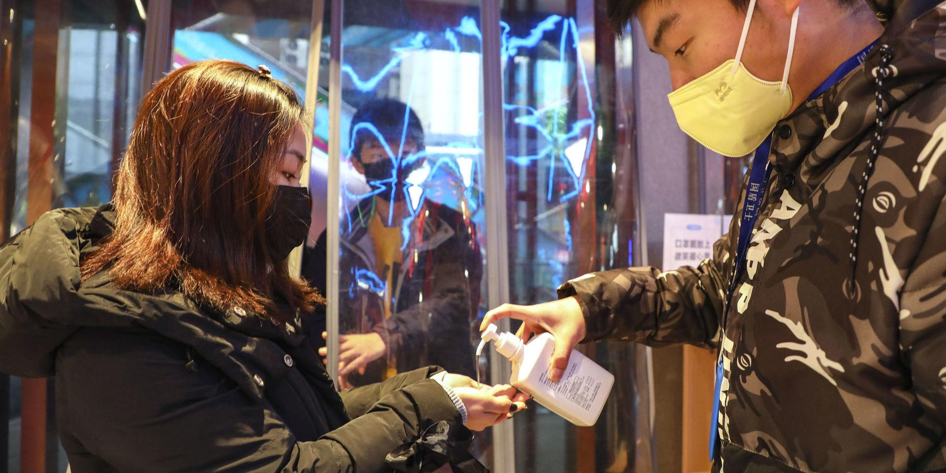 Kunder på ett köpcenter i Wuhan får handsprit av personalen. Arkivbild.