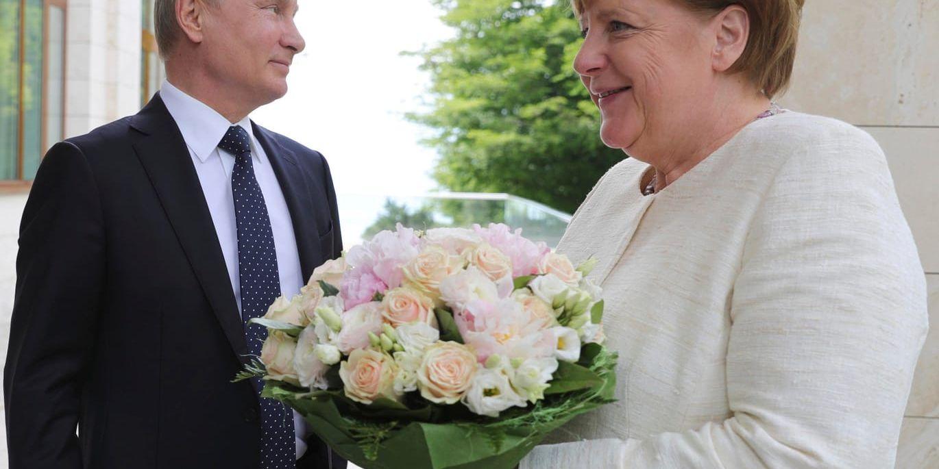 Rysslands president Vladimir Putin hälsade Tysklands förbundskansler Angela Merkel med en bukett blommor när hon besökte ryska semesterorten Sotji i maj. Arkivbild.