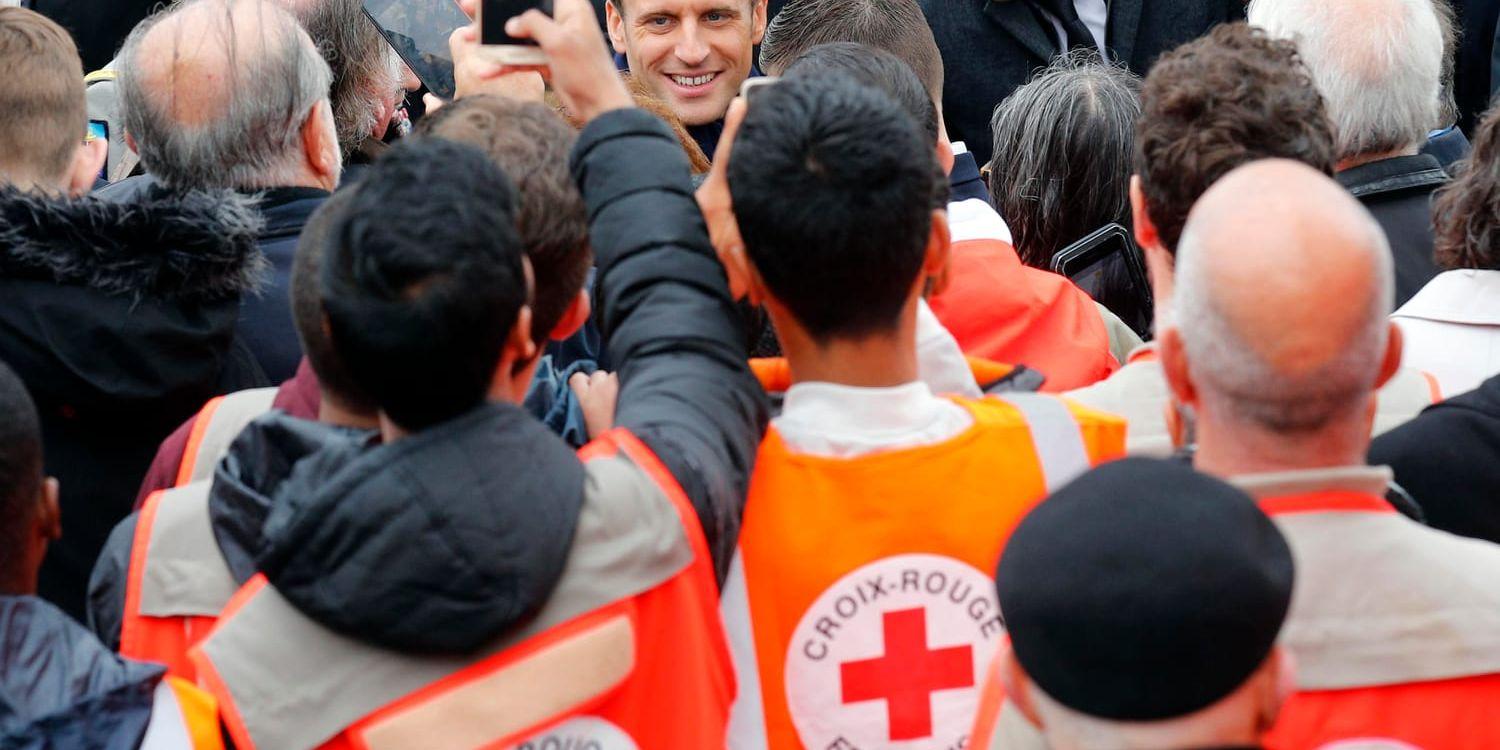 Frankrikes president Emmanuel Marcon omgärdad av frivilliga från Röda korset vid en ceremoni vid Triumfbågen den 8 maj. Arkivfoto.