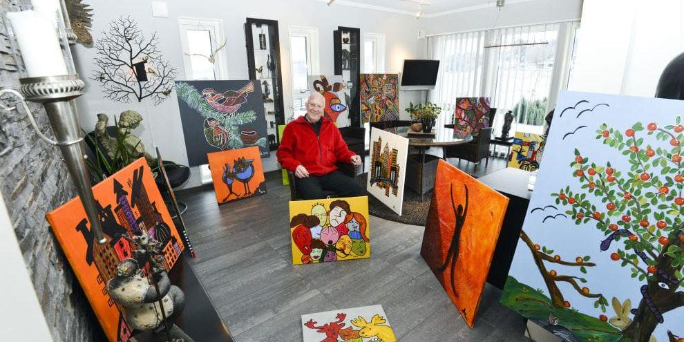 Omgiven av sin konst. John Lyrestedt i sitt vardagsrum hemma i Torpa med ett urval av sina målningar. På lördag ställer han och nio andra Varbergskonstnärer ut sina verk i Tofta konstgalleri.